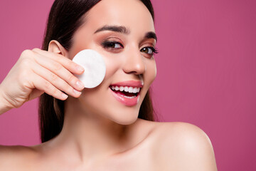 Wall Mural - Photo of positive girl using cotton disk face applying beauty product isolated on pink color background