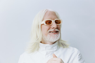 Portrait of a cheerful elderly man with long white hair and stylish sunglasses The background is neutral, enhancing his joyful expression, evoking a sense of positivity and freedom