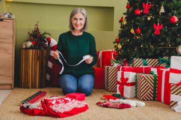 Photo of lovely cute retired lady pensioner wear green sweater packing new year gift present indoors house home room