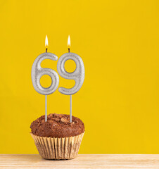 Chocolate cupcake with number 69 candle - Birthday on a yellow background.