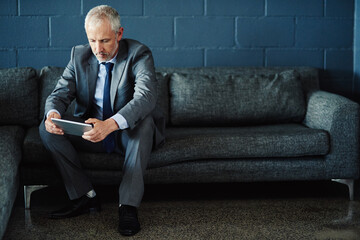 Leinwandbilder - Brick wall, sofa and tablet with mature businessman in office for online research or planning. Break, internet and technology with experienced employee on mockup space for email communication