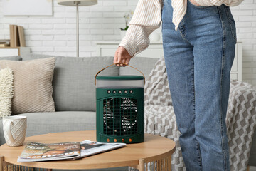 Woman with portable table fan on table at home