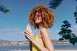© SHOTPRIME STUDIO - Woman enjoying ice cream at the beach in a sunny day, wearing stylish sunglasses and a bright swimsuit