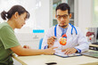 © NanSan - A doctor man sits at a desk in a hospital, explaining heart disease symptoms to a female patient. They discuss chest pain, palpitations, fatigue, dizziness, and the risks of myocardial ischemia