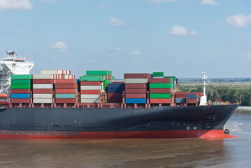 Wall Mural - A massive cargo ship loaded with containers maneuvers carefully during docking operations at the port of Charleston, USA. 