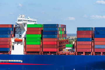 Wall Mural - A massive cargo ship loaded with containers maneuvers carefully during docking operations at the port of Charleston, USA. 