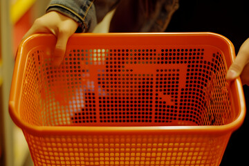 Close-up of orange shopping basket in grocery aisle, realistic everyday scene