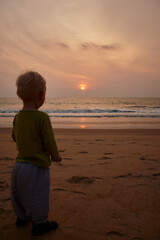 Sunset, boy and child on beach for vacation, adventure and explore by waves on summer holiday outdoor. Travel, male person and kid by seaside for playing, wellness and journey in nature on weekend