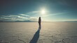 © Esmari - person standing on a vast salt flat landscape with the sun shining in the sky
