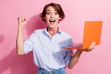 Wall Mural - Photo of delighted nice girl hold laptop raise fist shout yes hooray success isolated on pink color background