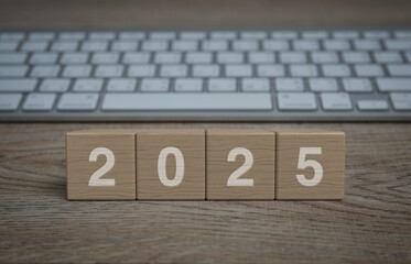 Wall Mural - 2025 letter on wood block cubes on wooden table with modern computer keyboard, Happy new year 2025 business online concept