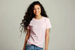 © EliteStock - A smiling young woman of Latin ethnicity with curly hair wears a light pink shirt, creating a cheerful and vibrant atmosphere.