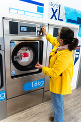 Wall Mural - Woman putting coins into automatic washing machine