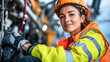 © kongkiat chairat - confident technician wearing safety helmet and bright work attire smiles while working on machinery. Her expression reflects pride in her role and dedication to safety