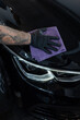 © alones - Professional man wiping car dry with microfiber in garage. Detailing studio, car care. Car polishing