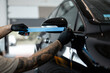 © alones - Professional man tapes black car before polishing. Detailing