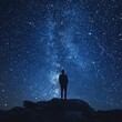 © Anastasiia - Silhouetted figure stands on rock under a starry night sky revealing constellations
