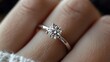 © horizon - Classic solitaire diamond engagement ring on a finger, featuring a white gold band and round brilliant cut diamond, set against a soft knit sweater with a delicate sparkle effect.