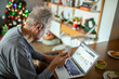 © Davor - Senior man managing finances online during Christmas at home