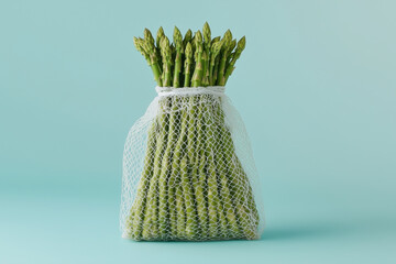 Set of raw asparagus with white net isolated on a blue background