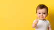 © Ajmeer - a toddler giving a thumbs up on yellow background