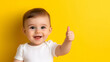 © Ajmeer - a toddler giving a thumbs up on yellow background