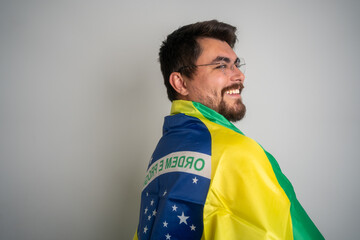 Cheerful man with a Brazilian flag on his back. Smiling cheerful Brazilian man with Brazilian flag looking at the camera. Brazilian flag, symbolizing patriotism and national pride. Brazilian 