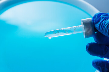 Wall Mural - blue science experiment background,dripping liquid from pipette into test tube in laboratory, closeu