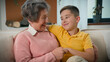 © Yuliia - Loving Caucasian grandmother elderly woman fun spend weekend with grandson kid boy child at home on cozy sofa smiling happy family two generations playing tickling hugging laughing tickle communicate