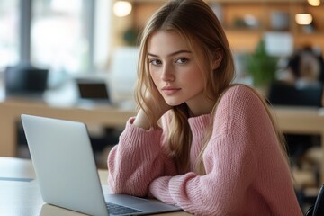 Serious thoughtful young university student girl typing on laptop in public library, thinking on report, article, essay, research paper, studying on Internet, sitting at table with open books