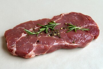 Raw beef steak with herbs on neutral background