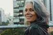 © darshika - natural portrait of older woman with gray hair in the city  smiling and looking at infinity.