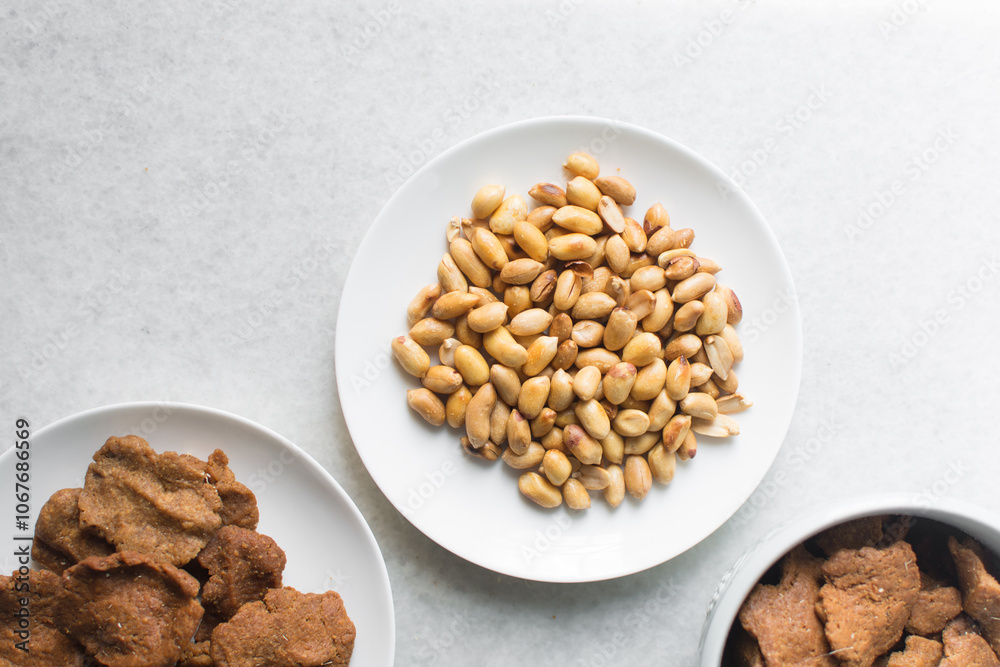 Overhead view of kuli-kuli and roasted peanuts on a white plate, top ...