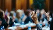 © imran - Blurred hands raised in a crowd discussing suggestions or voting in a council meeting -