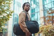 © Mikhail Vorobev - Stylish young black man posing outdoors with duffle bag, exuding confidence and attitude