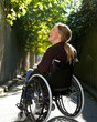 © Luluraschi - a smiling woman in a wheelchair, sitting comfortably on a sunlit street