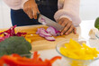 © Wavebreak Media - Asian woman chopping red onion on cutting board with colorful vegetables in kitchen, at home