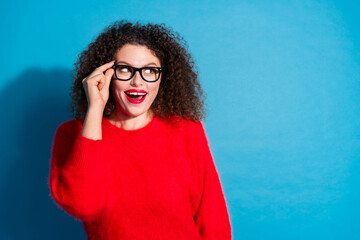 Photo of attractive young woman look empty space touch specs interested dressed stylish red clothes isolated on blue color background