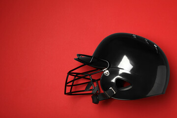 Black baseball helmet on red background, top view. Space for text