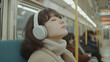 © pattozher - Peaceful Commute: Serene young woman enjoys tranquil moment on public transport, wearing headphones.