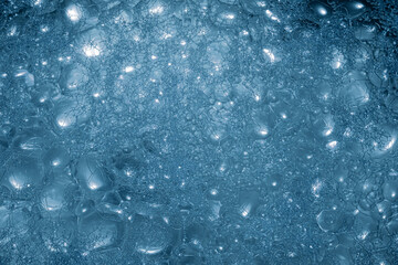 a close-up view reveals a multitude of blue bubbles clustered together, reflecting diffused light, c