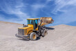 © kvdkz - Powerful wheel loader or bulldozer. The loader transports crushed rock or gravel in a large bucket. Powerful modern technology. Construction equipment rental
