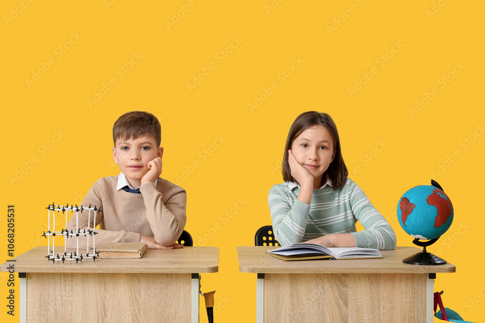 Cute children with molecular model and globe sitting at school desks on yellow background