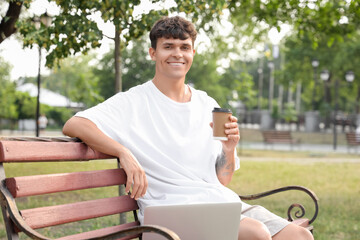 Poster - Handsome young man with laptop and cup of delicious latte sitting on bench outdoors