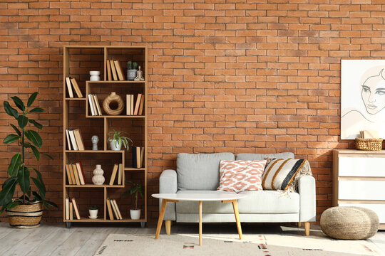 Cozy sofa, shelving unit and chest of drawers in interior of living room