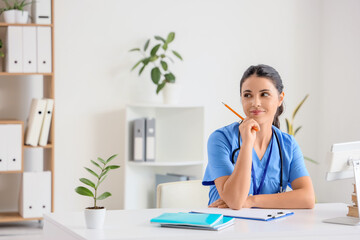 Poster - Young female medical student sitting at table in clinic