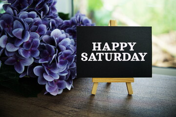 Wall Mural - happy saturday text on paper card with ealsel on wooden background