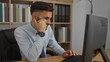 © Krakenimages.com - Young hispanic man with beard working at computer in office, appearing thoughtful and focused