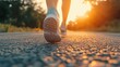 © tashechka - A runner's feet strike the asphalt as the sun sets, casting warm light over the peaceful road ahead