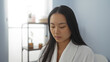 © Krakenimages.com - Woman relaxing in a serene spa room wearing a white robe, with shelves holding potted plants in the background, creating a calming and attractive wellness setting indoors.